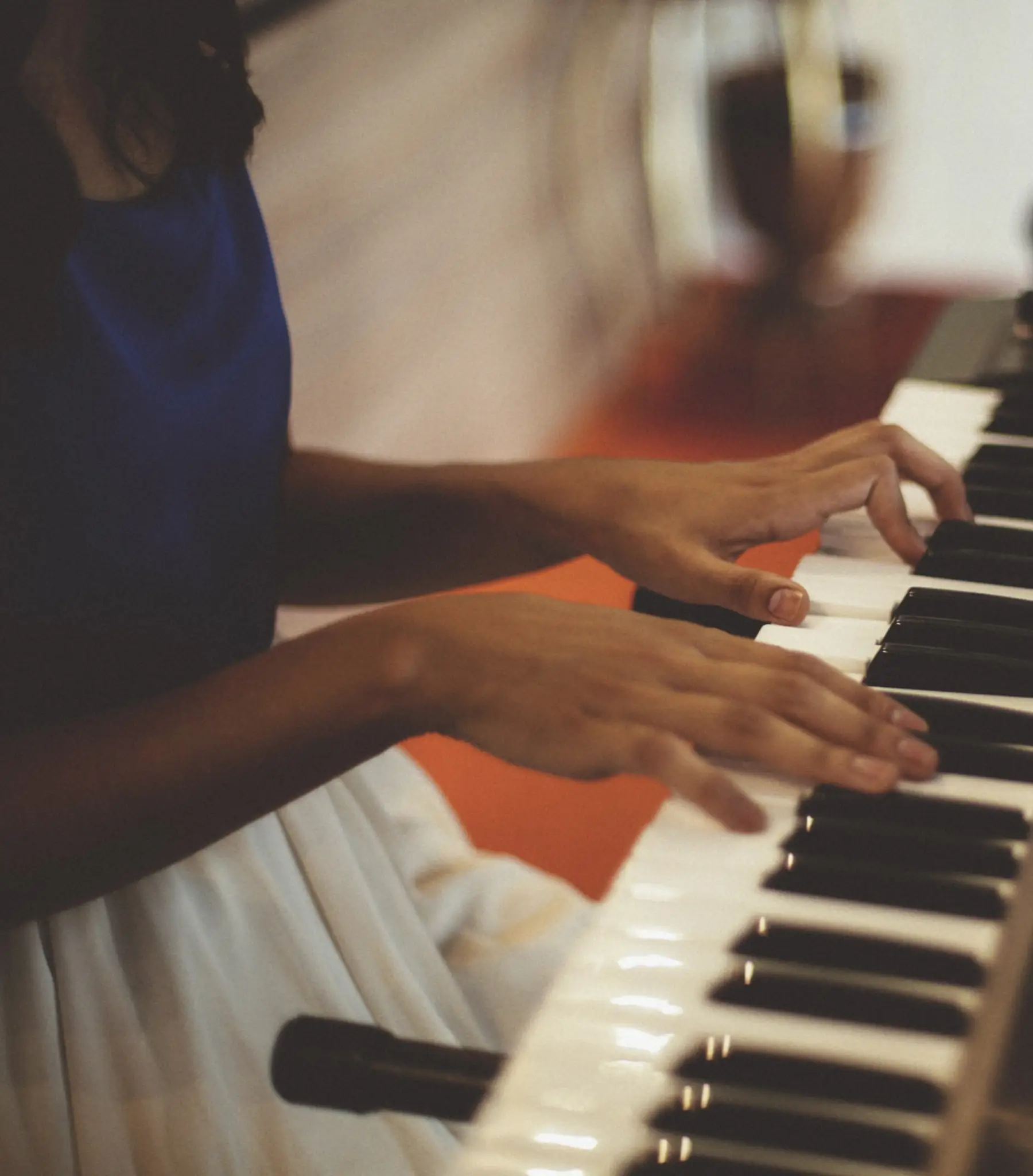 Zwei Hände spielen auf den Tasten eines Keyboards, Nahaufnahme von der Seite